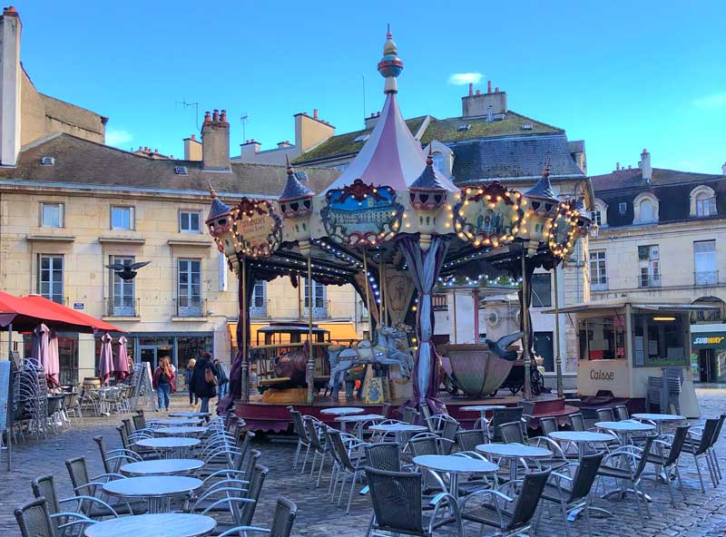 Place pavée avec un carrousel au centre, bordée de vieux bâtiments à Dijon, Bourgogne