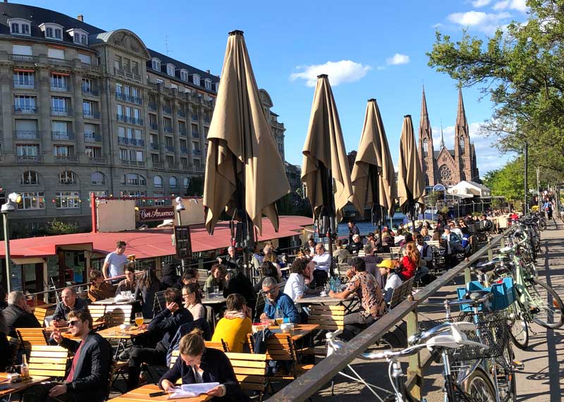 Beaucoup de gens assis au Quai des Pêcheurs en sirotant un verre au soleil à Strasbourg