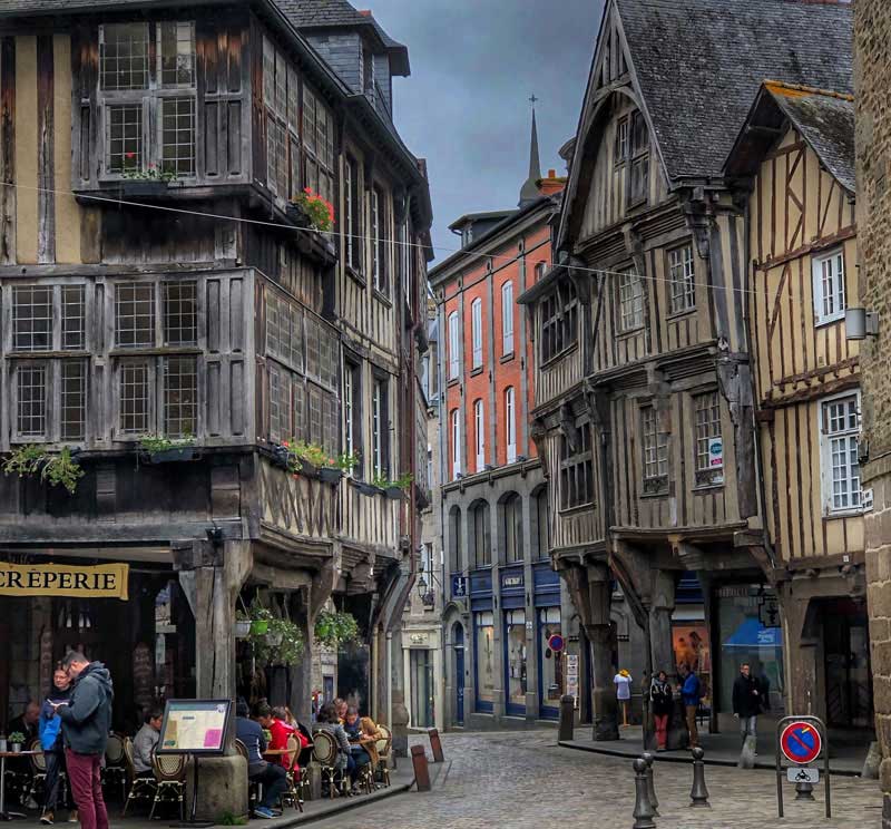Place pavée bordée de maisons à pans de bois avec boutiques à arcades et restaurants
