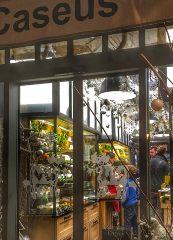 Fromagerie décorée de boules et de fleurs fraîches, étagères remplies de fromages français