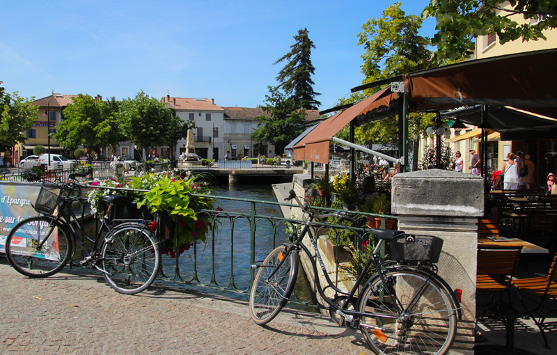 Des vélos le long d'une rivière par une journée ensoleillée dans la ville de l'Isle-sur-la-Sorgue, Provence