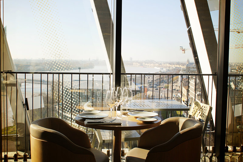 Table et chaises sur un balcon au 7ème étage du musée de la Cité du Vin avec vue sur Bordeaux
