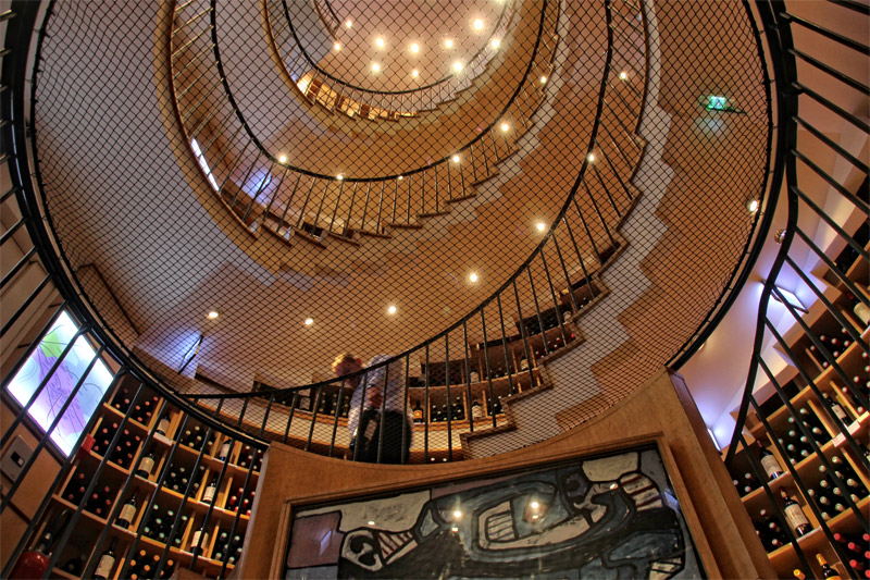 Un caviste à Bordeaux avec un escalier en colimaçon qui monte sur 5 étages, bordé de casiers à vin