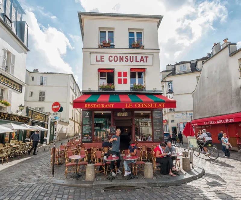 Célèbre café à Montmartre Paris, Le Consulat dans une rue pavée, les gens s'assoient à des tables et des chaises sur la terrasse