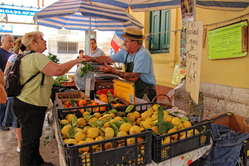 Une femme achète des citrons frais dans un étal du marché de Menton, dans le sud de la France